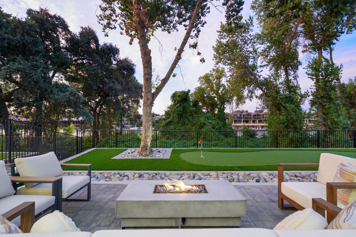 Gas fire pit with lounge seating under mature trees at dusk