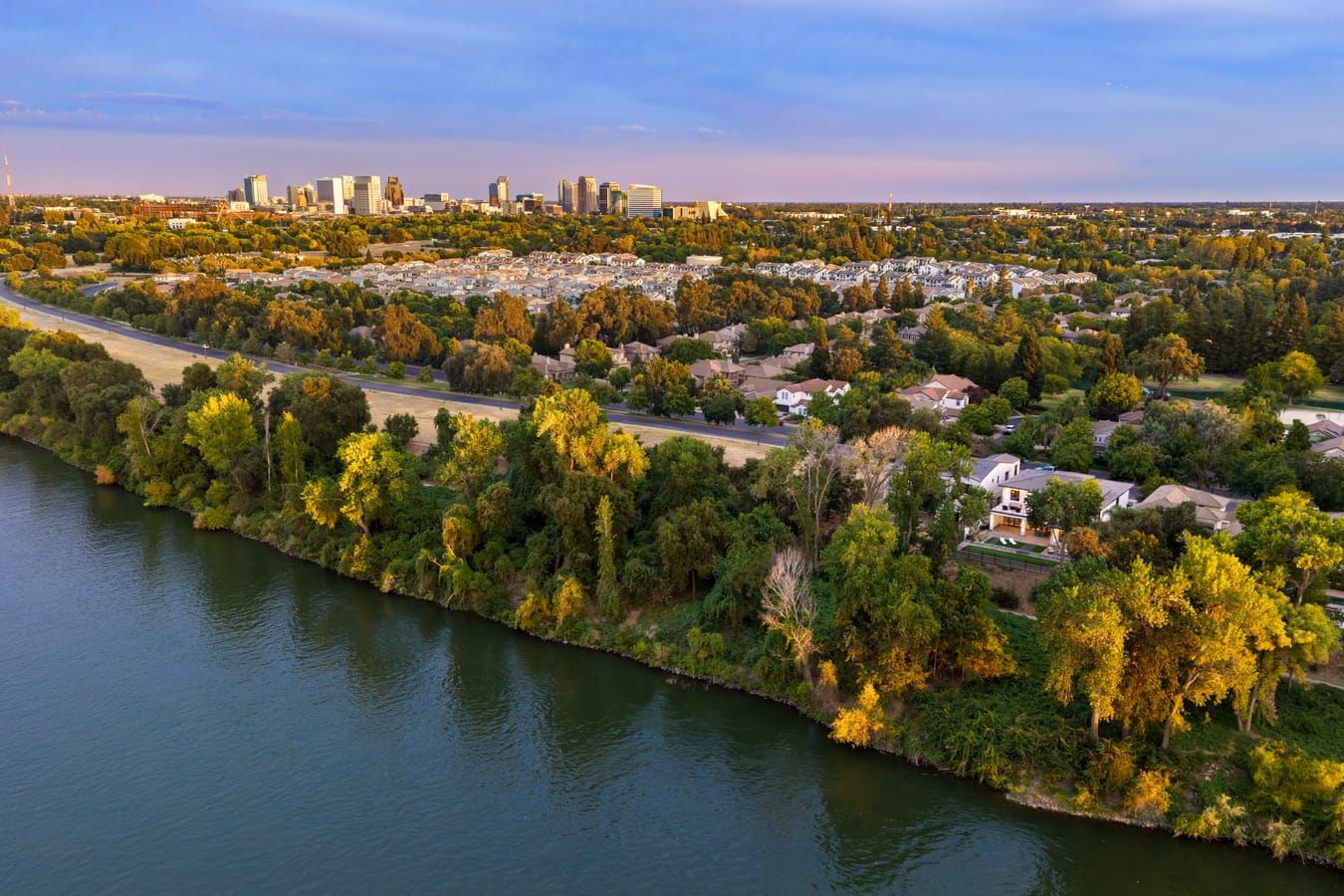Aerial view at golden hour of the Sacramento River and The Rivers community, with the downtown Sacramento skyline beyond
